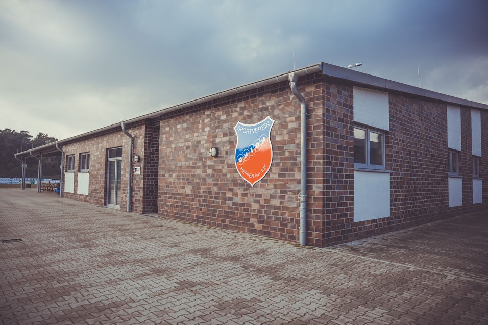 Fassade eines Sportgeb&auml;udes mit einem Wappen und Fenster in einem modernen Backsteindesign.