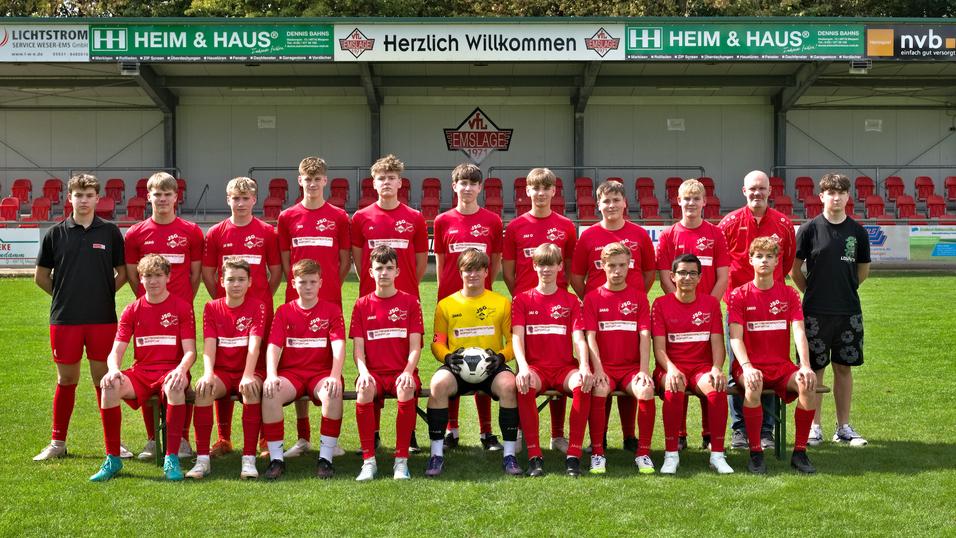 Teamfoto einer Jugendfu&szlig;ballmannschaft in roten Trikots mit einem Fu&szlig;ball, auf einem gr&uuml;nen Rasenplatz.
