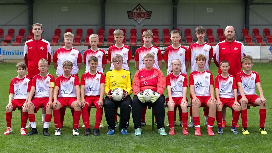 Gruppenfoto einer Fu&szlig;ballmannschaft mit 18 Spielern in roten Trikots und zwei Torwarten auf einem gr&uuml;nen Platz.