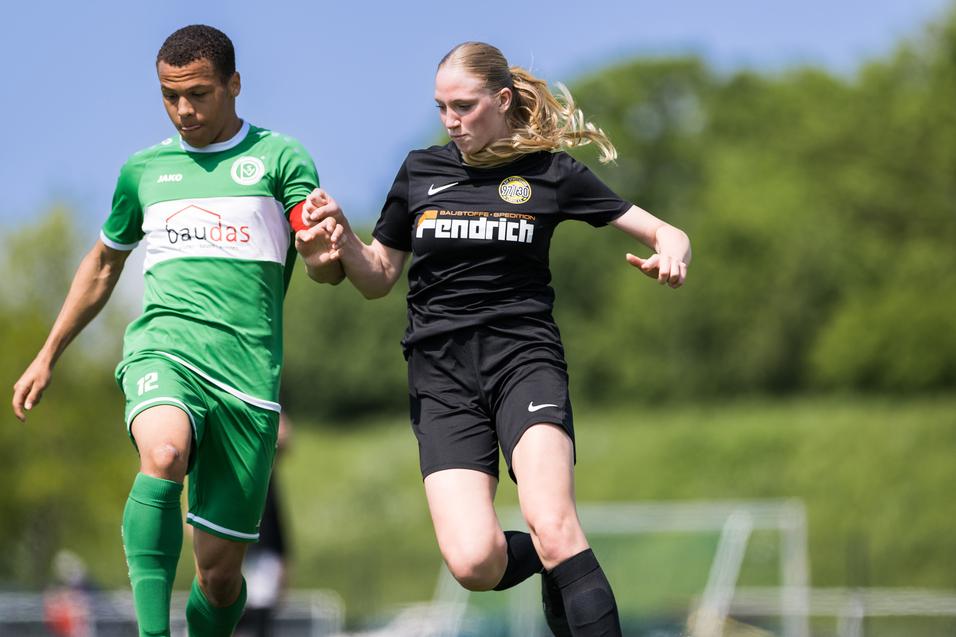 Zwei Fußballspieler im Wettkampf, einer in grün-weißer und der andere in schwarzer Sportkleidung.